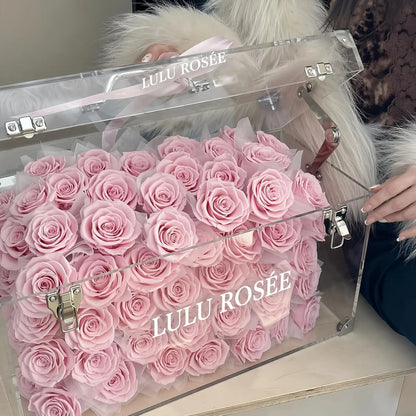 LULU ROSÉE Grande Eternal Acrylic Handbag Rose Box, luxury handbag-shaped transparent acrylic gift box filled with blush pink preserved roses, flat tabletop closeup display, customizable flower colors, romantic everlasting floral souvenir for anniversary & birthday gifting