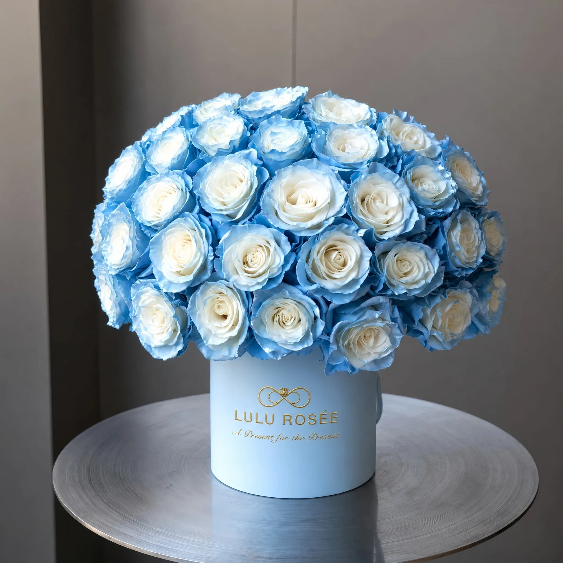 LULU ROSÉE Grande Superdome Ice Blue Gradient Preserved Rose Box, side view of full superdome arrangement of gradient ice blue everlasting roses in branded cylinder box